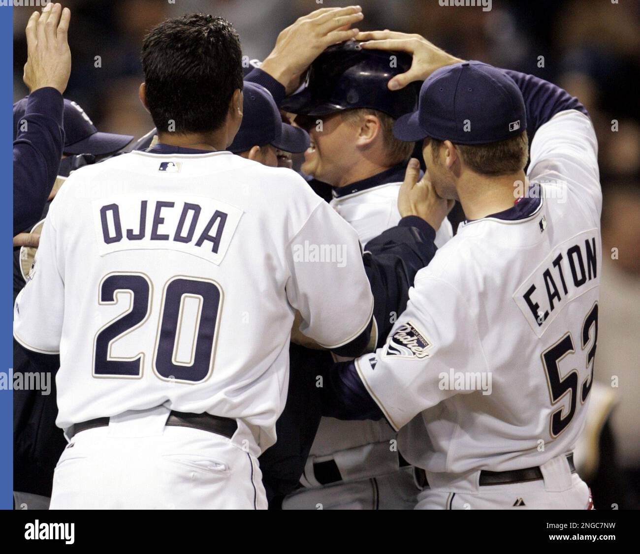 San Diego Padres' Miguel Ojeda and Adam Eaton lead the way as the Padres mob teammate Geoff Blum after he scored the winning run in the 12th inning of the Padres' 1-0 victory over the Pittsburgh Pirates on Thursday, April 7, 2005. in San Diego. Blum scored on a bases-loaded walk to Xavier Nady. (AP Photo/Lenny Ignelzi) Stockfoto
