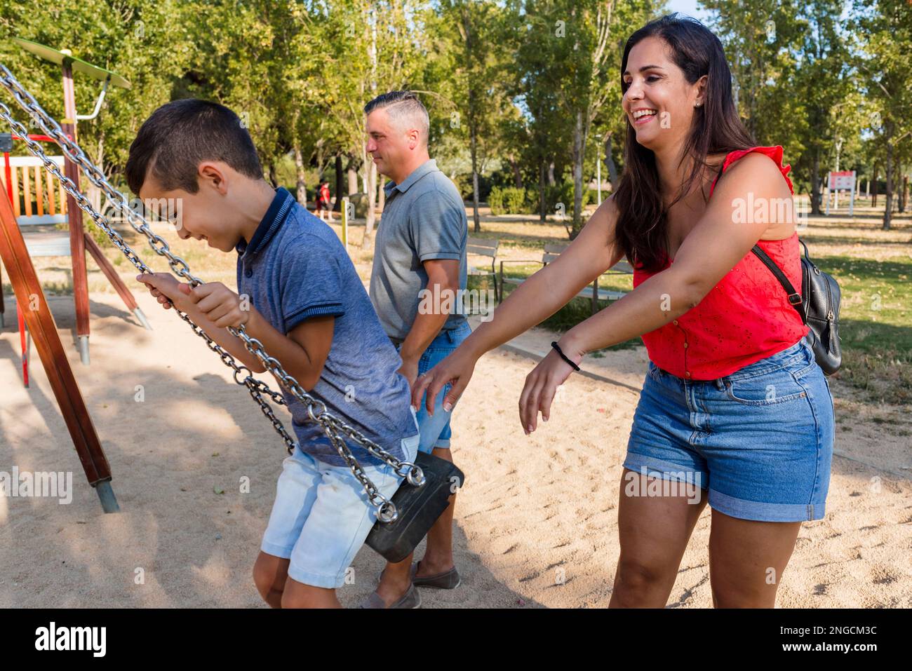 Ein Paar und ein Sohn haben Spaß beim Spielen mit der Schaukel im Park. Stockfoto