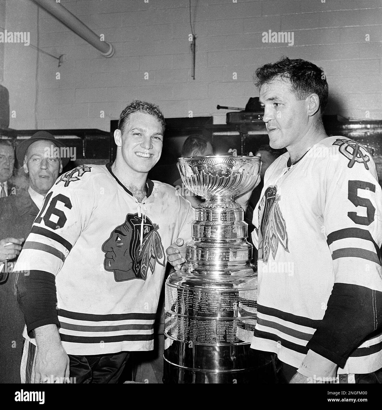 Bobby Hull (16) and Jack Evans (5) of the Chicago Black Hawks pose with the Stanley Cup trophy in the dressing room after the Hawks defeated the Detroit Red Wings 5-1 in Detroit, Mich., on Sunday, April 16, 1961. The Black Hawks win their first Stanley Cup title in 23 years. (AP Photo) Stockfoto