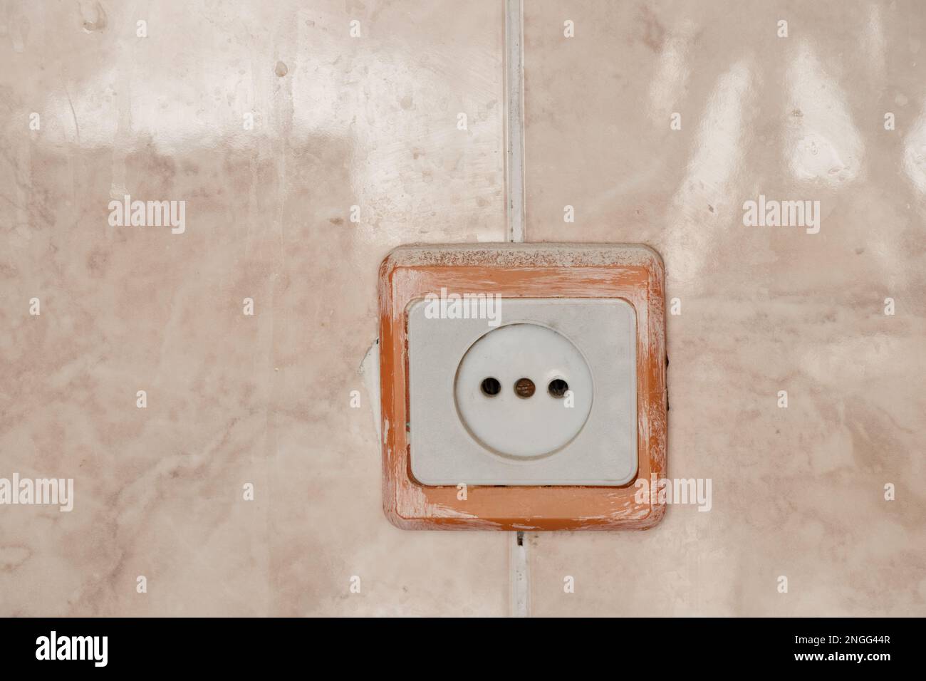 Alte weiße Kunststoffsteckdose an der Wand der Fliesen in der Küche Stockfoto