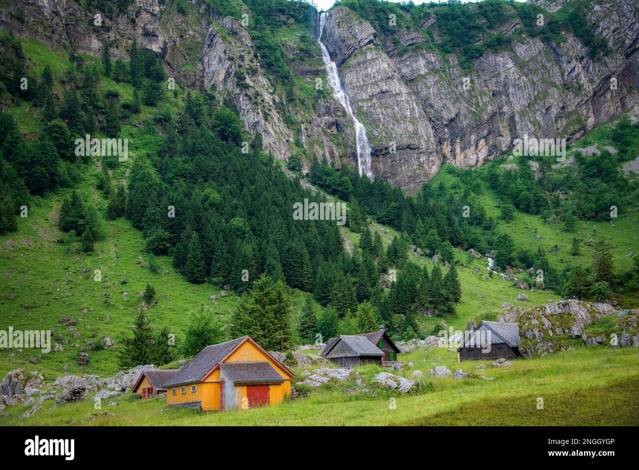 Bauernhäuser zwischen Bergen im Hintergrund ein Wasserfall Stockfoto