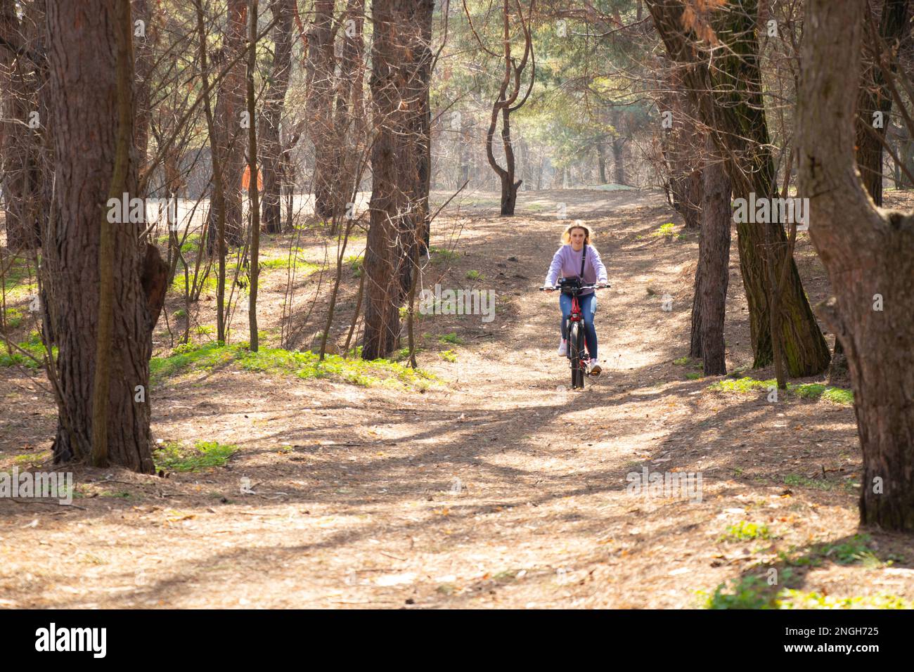 Mädchen fährt mit einem E-Bike im Frühlingswald in der Ukraine in der Stadt Dnipro, Outdoor-Erholung Stockfoto