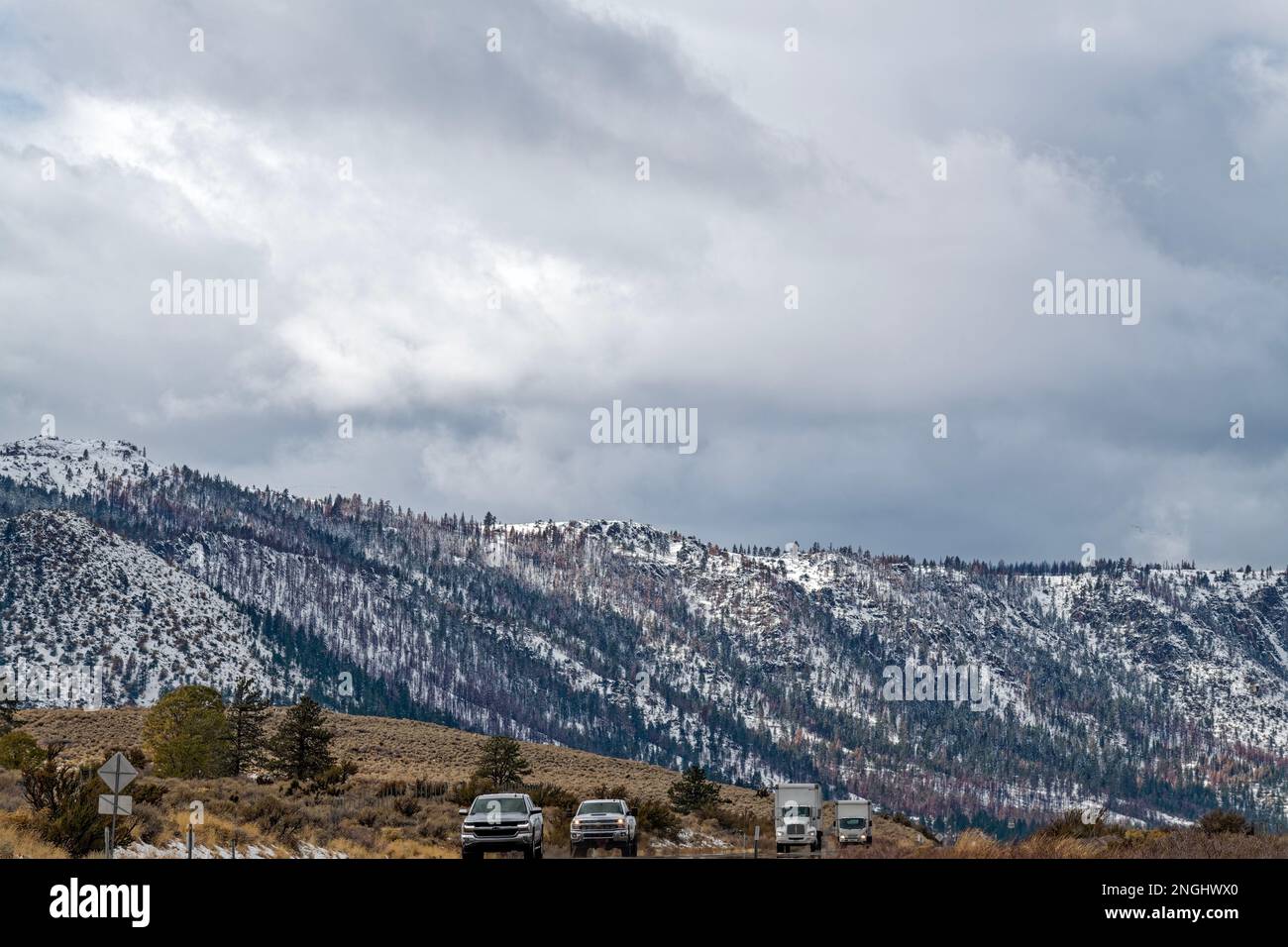Der Verkehr verläuft entlang der USA Highway 395 vor der Kulisse verschneiter Berge in der Nähe von Milford, Kalifornien, USA Stockfoto