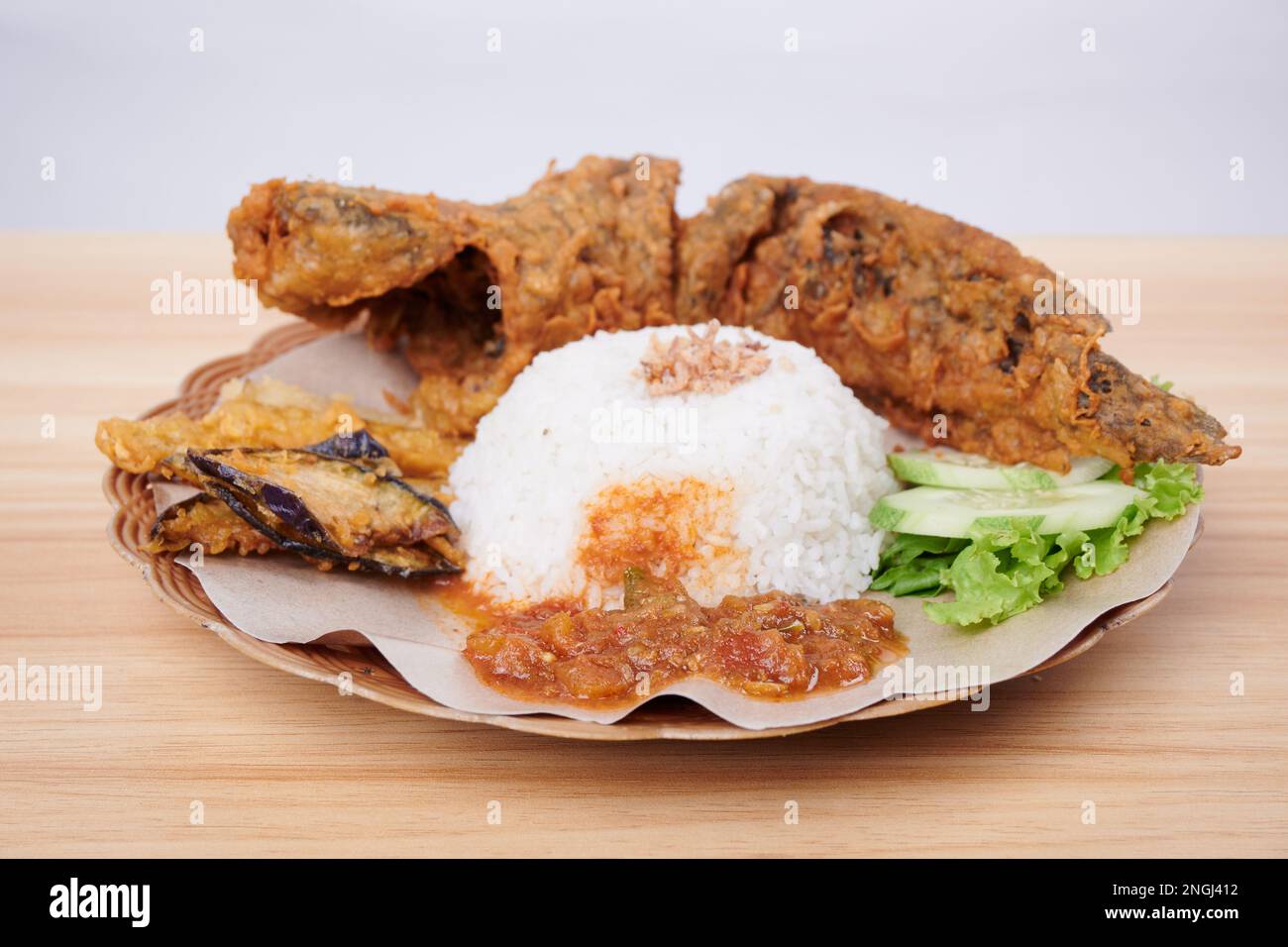 Gebratener Catfish mit scharfer Sauce, Reis und Gemüse auf einem Teller (Pecel Lele) Stockfoto