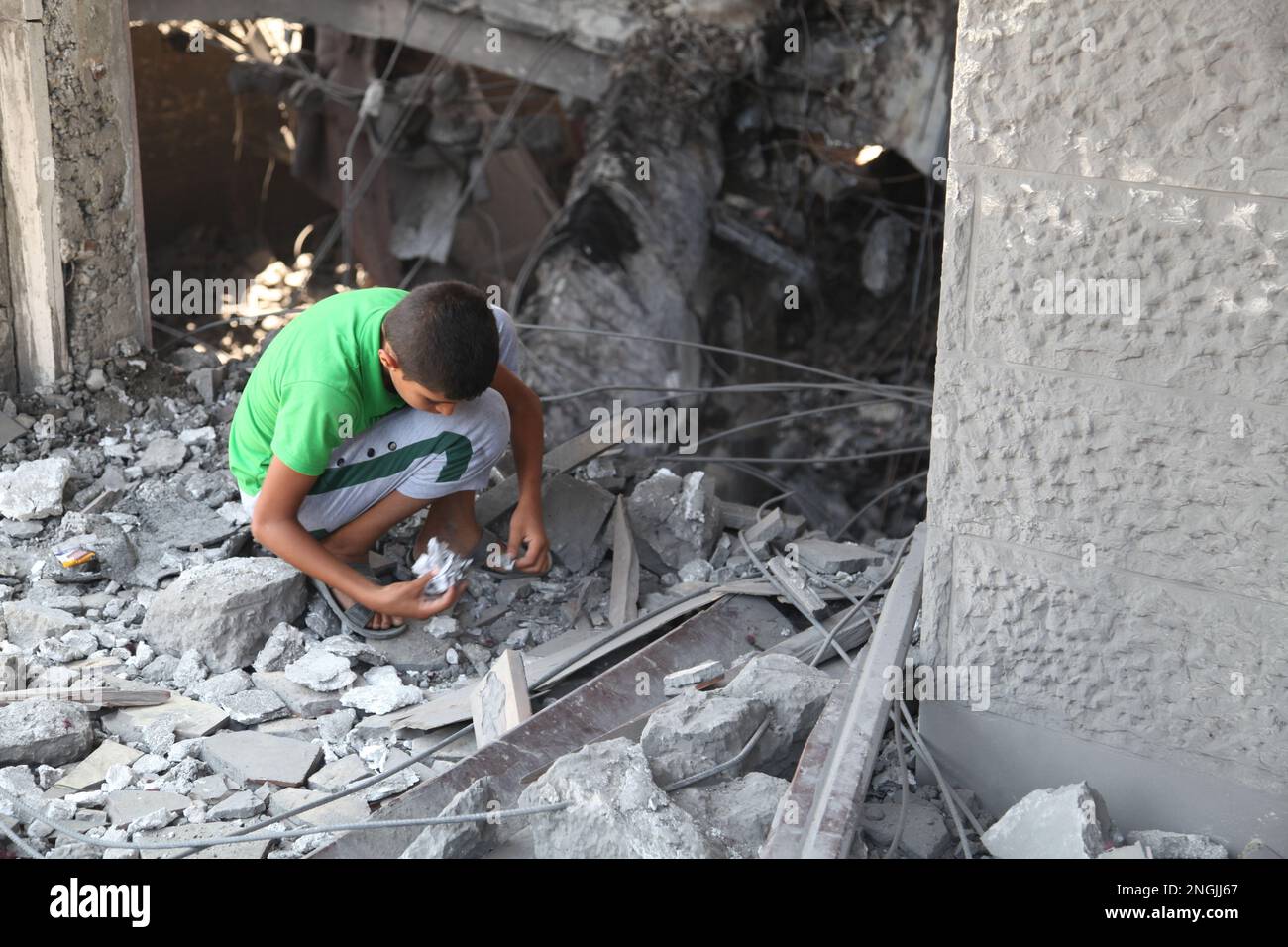 Gaza, Palästina. Ein Kind, das nach seinem Spielzeug sucht, auf dem, was von dem zerstörten Haus übrig ist, von den israelischen Streitkräften Stockfoto