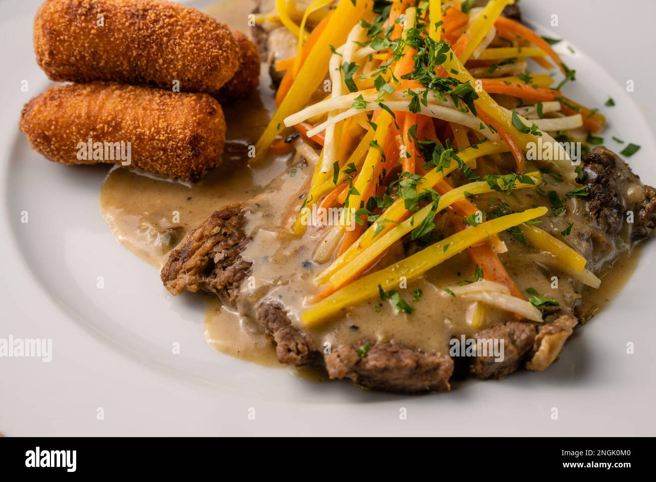 Esterhazy Roast Beef oder Rostbraten mit Wurzelgemüse Julienne, Kroketten und saurer Soße Stockfoto