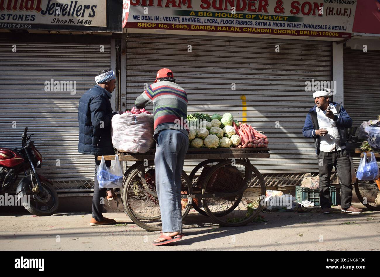 Ein Frischgemüsehändler, der Produkte wie Möhren und Kohl von einem Karren in den Straßen von Old Delhi verkauft Stockfoto