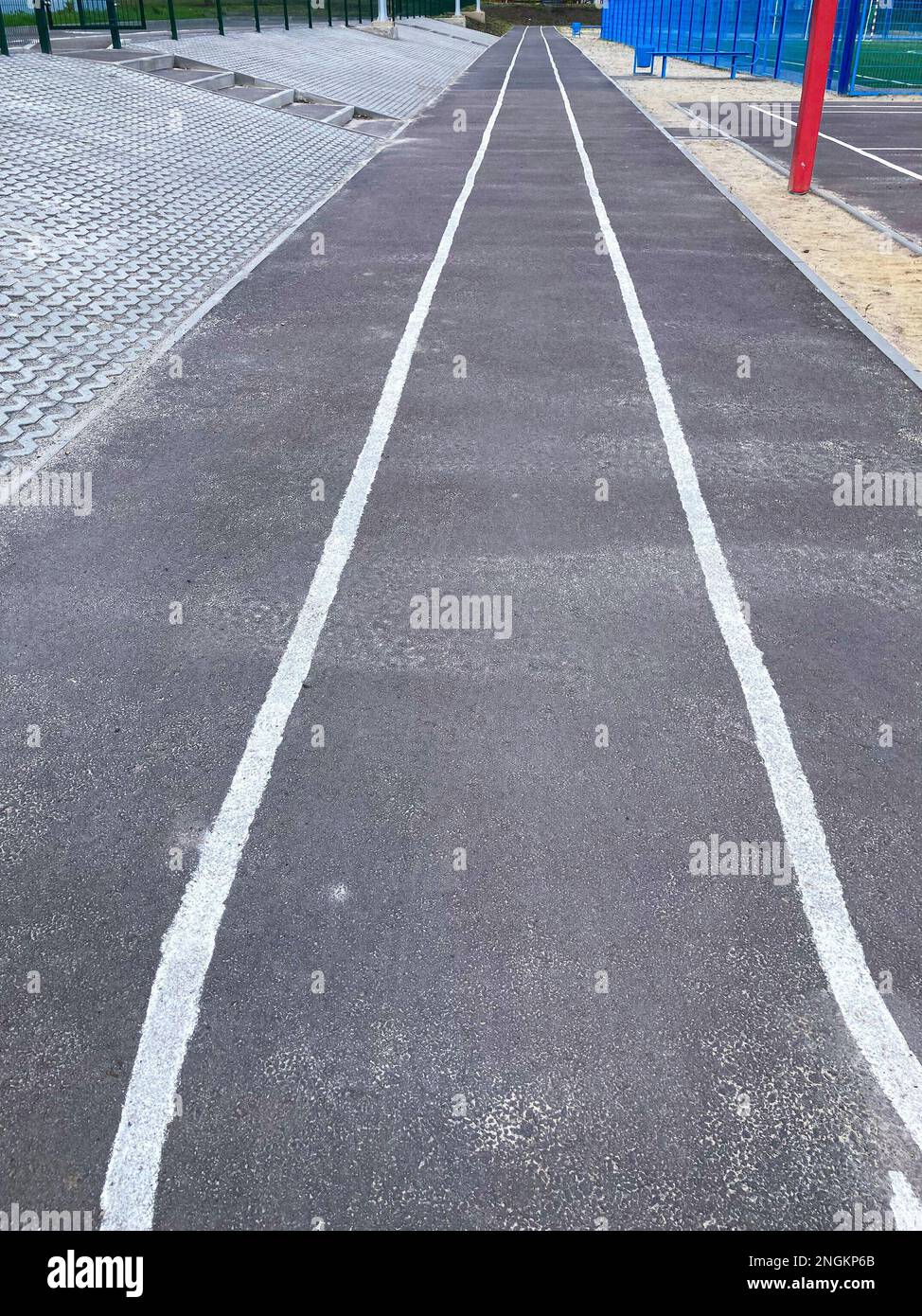 Sporttretband. Asphaltierte Laufstrecke, Sport, 4 Reihen. Der Schulsportplatz. Neues Sprint-Detail des Stadions Stockfoto