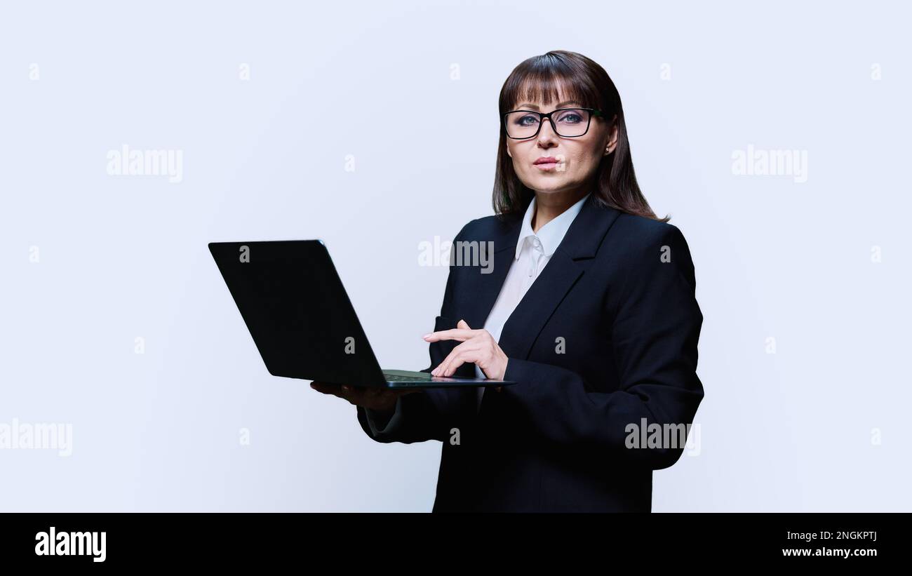Reife Geschäftsfrau, die mit einem Notebook auf weißem Hintergrund posiert Stockfoto