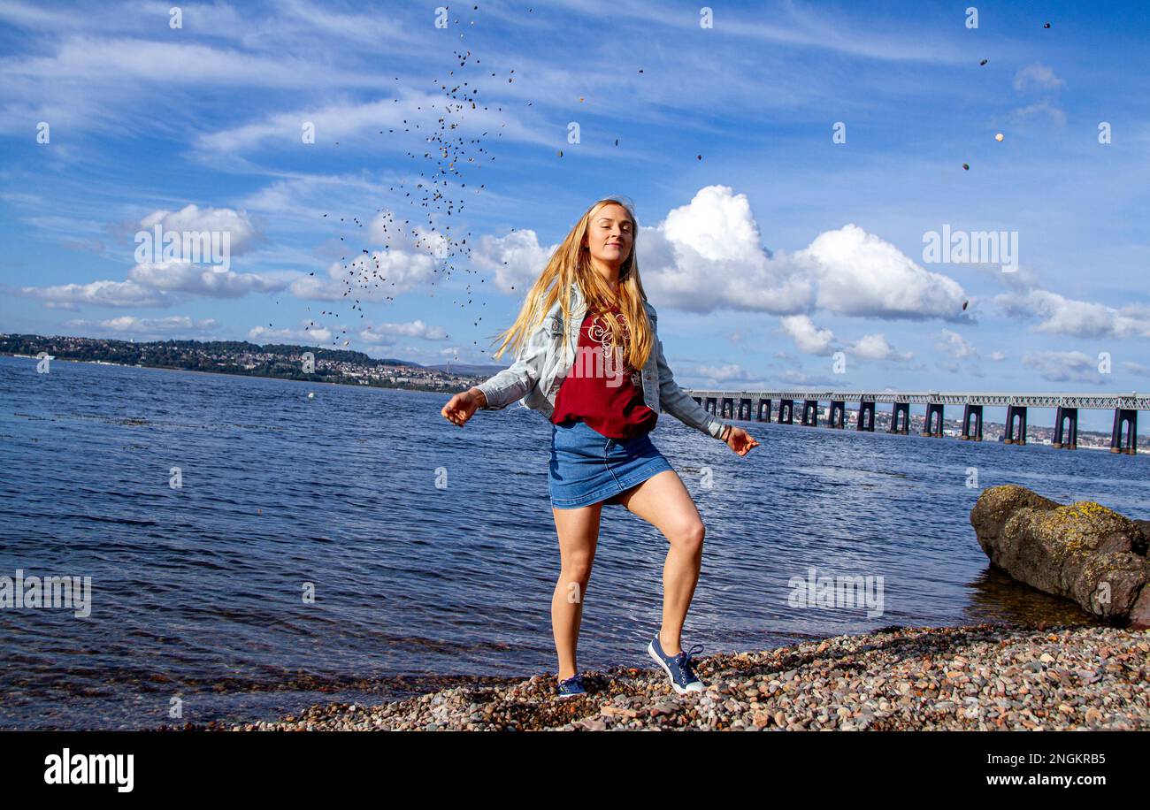 An einem wunderschönen Oktobertag in Wormit Beach, Fife, wirft Rhianna Martin Kiesel über ihren Kopf in den Fluss Tay, Schottland Stockfoto