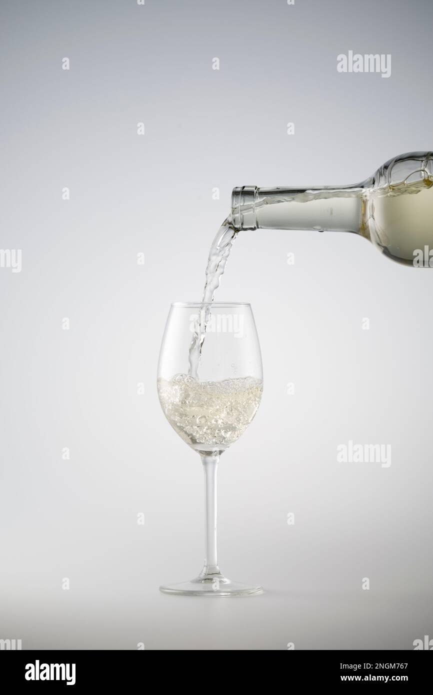 Weißwein wird in ein Weinglas gegossen Stockfoto