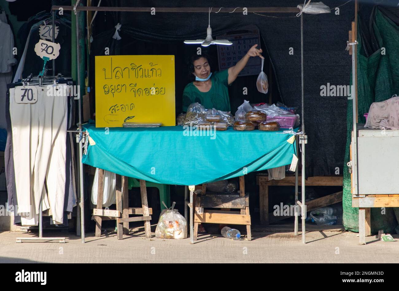 SAMUT PRAKAN, THAILAND, FEBRUAR 13 2023, Ein Verkäufer auf dem Markt bietet Minnow und ein Produkt aus getrockneter Mango an Stockfoto