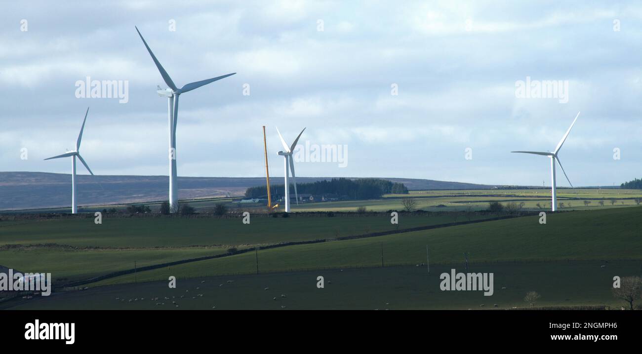 Landschaft mit einem Flickenteppich von Sonnenlicht auf Ackerland mit Windturbinen in der Mitte Stockfoto