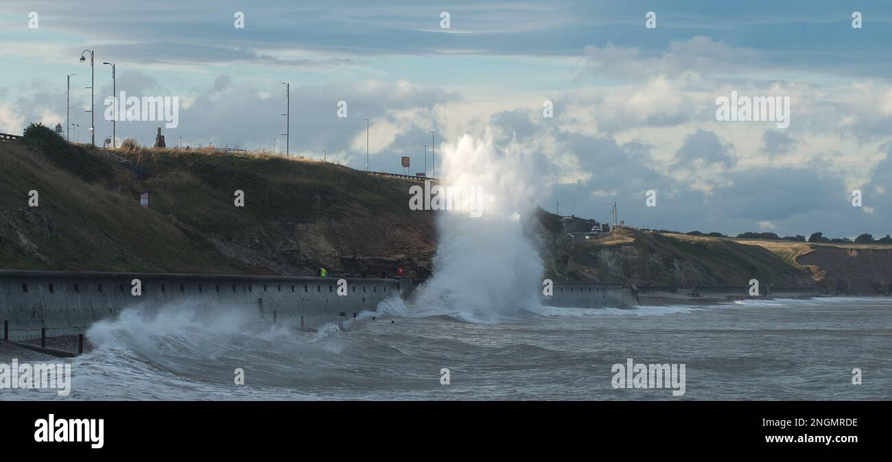 Mächtige Wellen schlagen auf die Promenade von Seaham und werfen eine riesige Sprühfahne, die von der späten Nachmittagssonne gefangen wurde Stockfoto