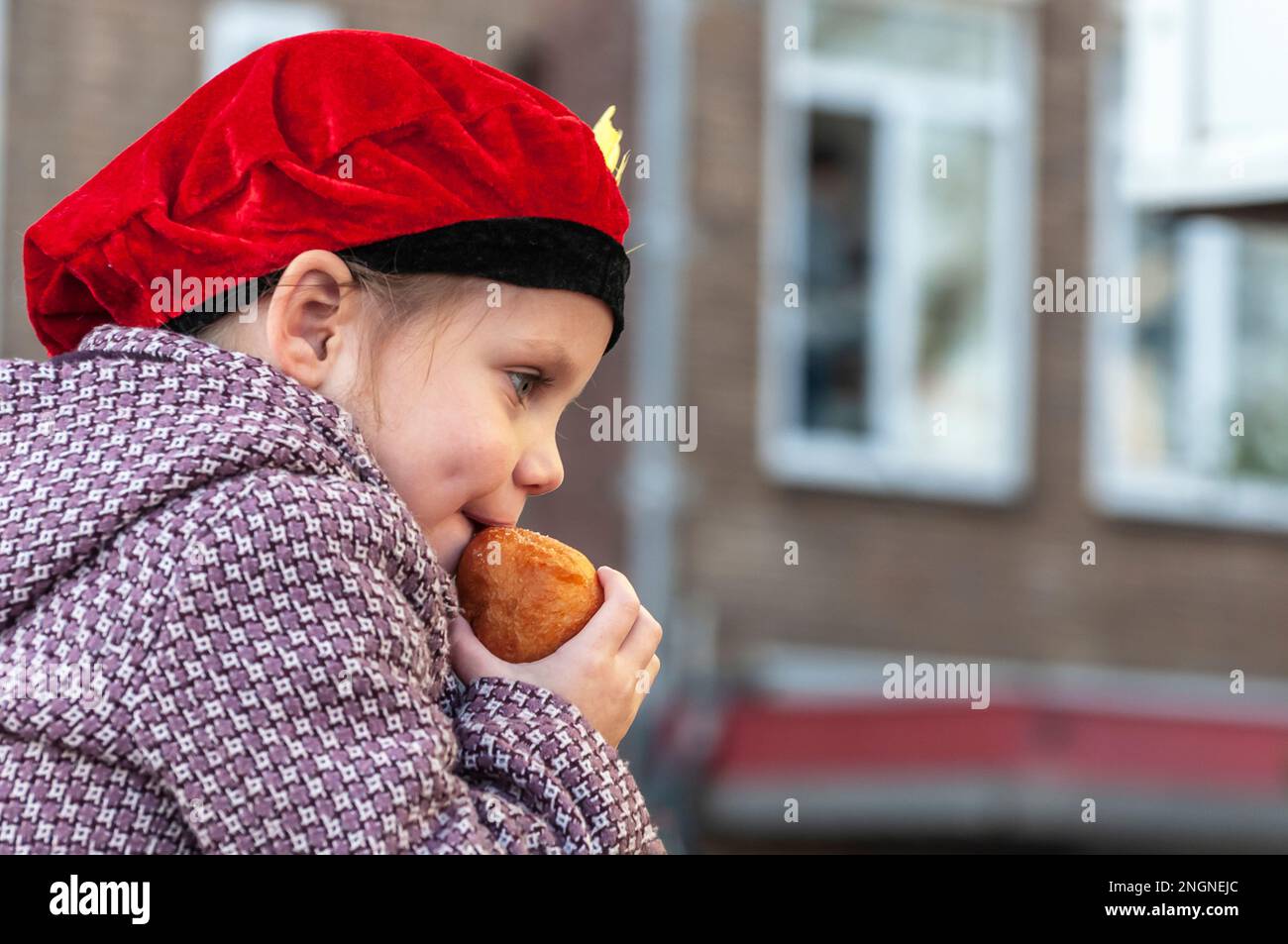 jong meisje traf een zwarte piet muts Eet een oliebol Stockfoto