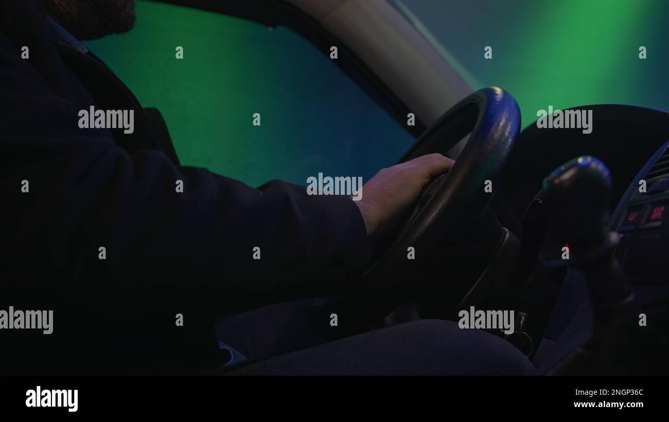 Nahaufnahme eines selbstbewussten männlichen Fahrers, der ein Fahrzeug mit Präzision und Kontrolle auf einer Tunnelstraße lenkt Stockfoto