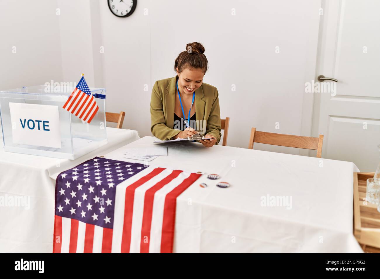 Junge schöne hispanische Frau Wahltisch Präsident schriftlich auf Zwischenablage an Wahlhochschule Stockfoto