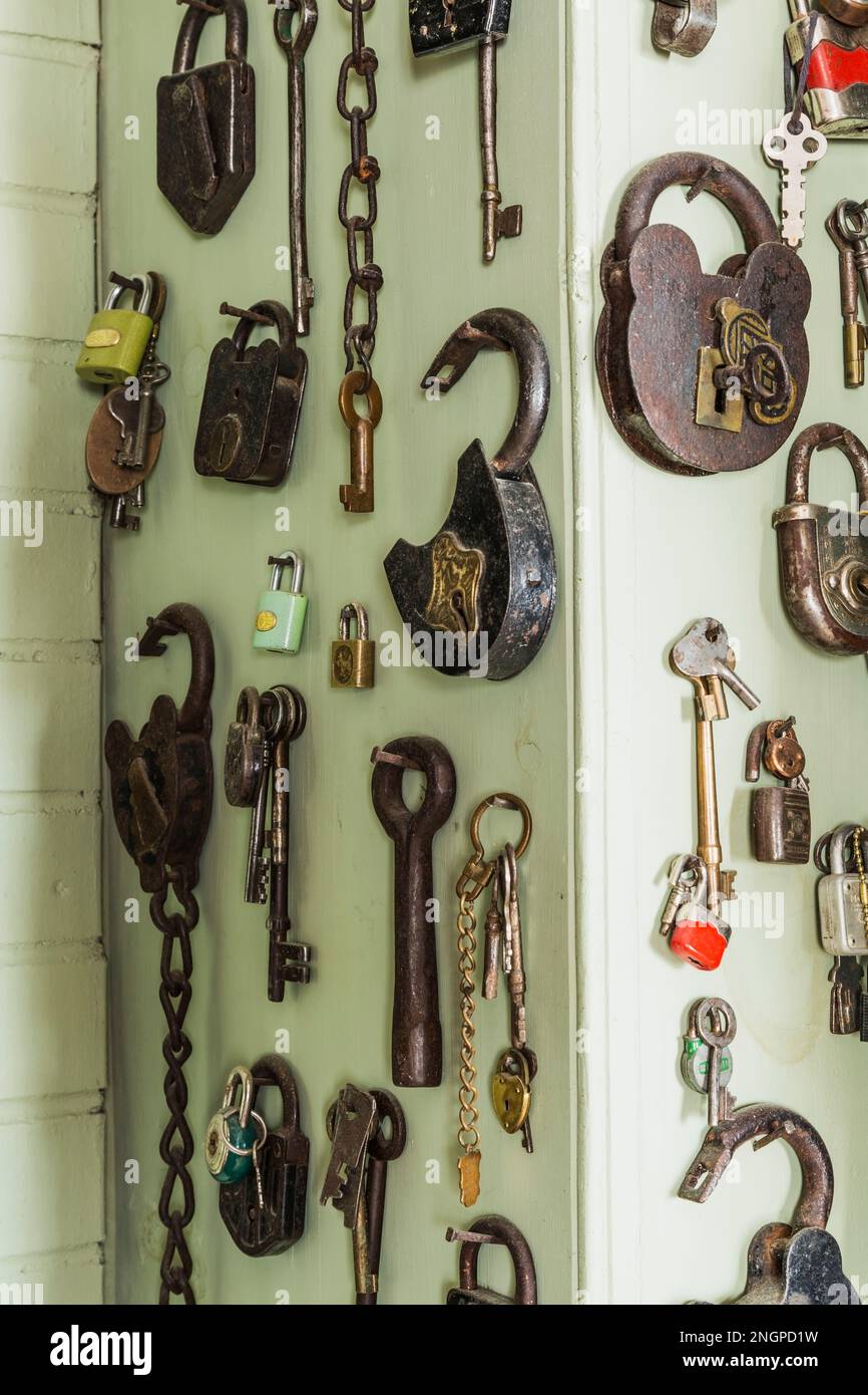 Nahaufnahme verschiedener Metallvorhängeschlösser und Schlüssel an grüner Wand in der Küche im alten Canadiana Landhaus aus dem Jahr 1835. Stockfoto