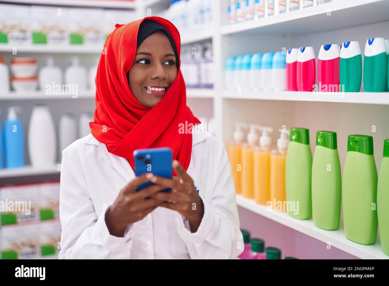Junge, schöne Apothekerin mit Smartphone, die in der Apotheke arbeitet Stockfoto