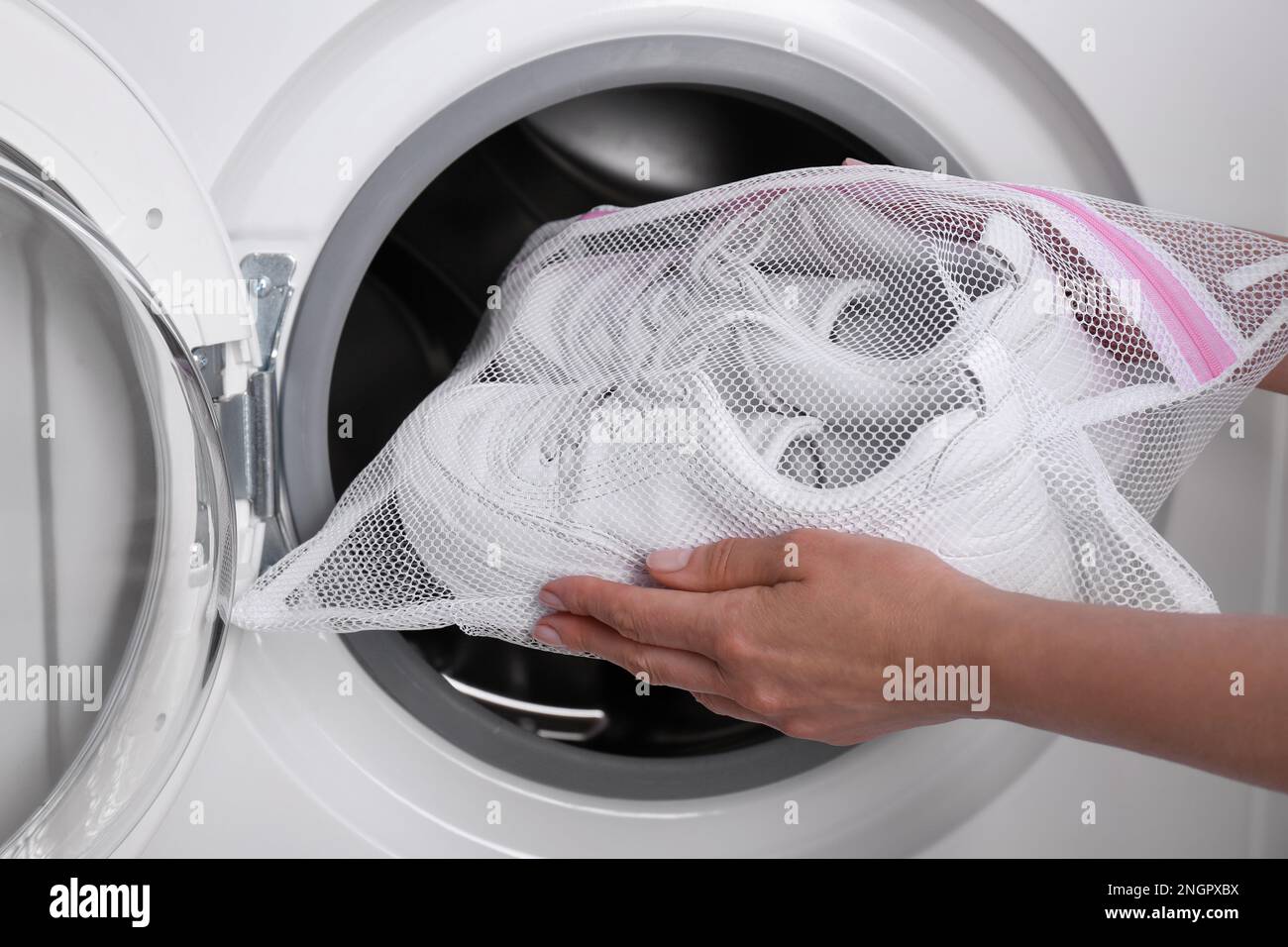 Eine Frau, die Sportschuhe in einen Wäschesack aus Netzgewebe in die  Waschmaschine steckt, macht Schluss Stockfotografie - Alamy