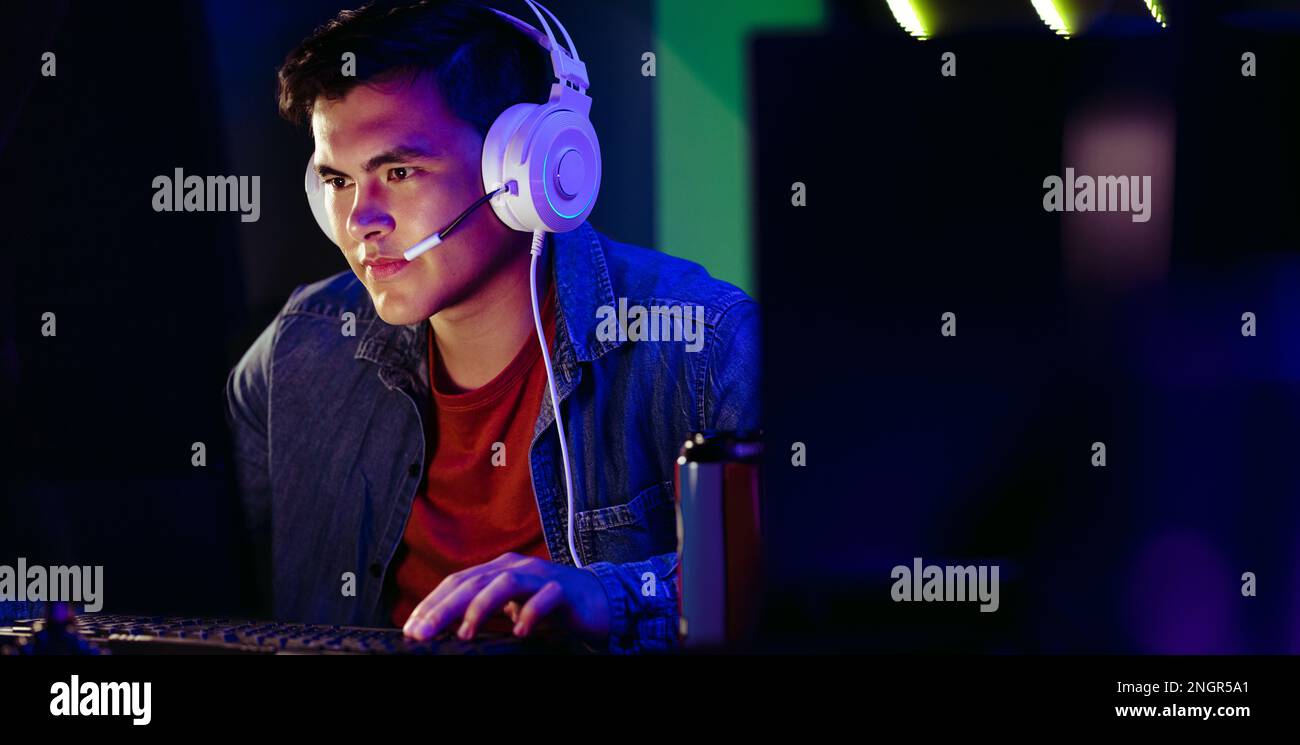 Ein Spieler schaut auf seinen Computerbildschirm und denkt über seinen nächsten Schritt in einem Online-Videospiel nach. Männlicher Gamer, der in die digitale Gaming-Welt eintaucht Stockfoto