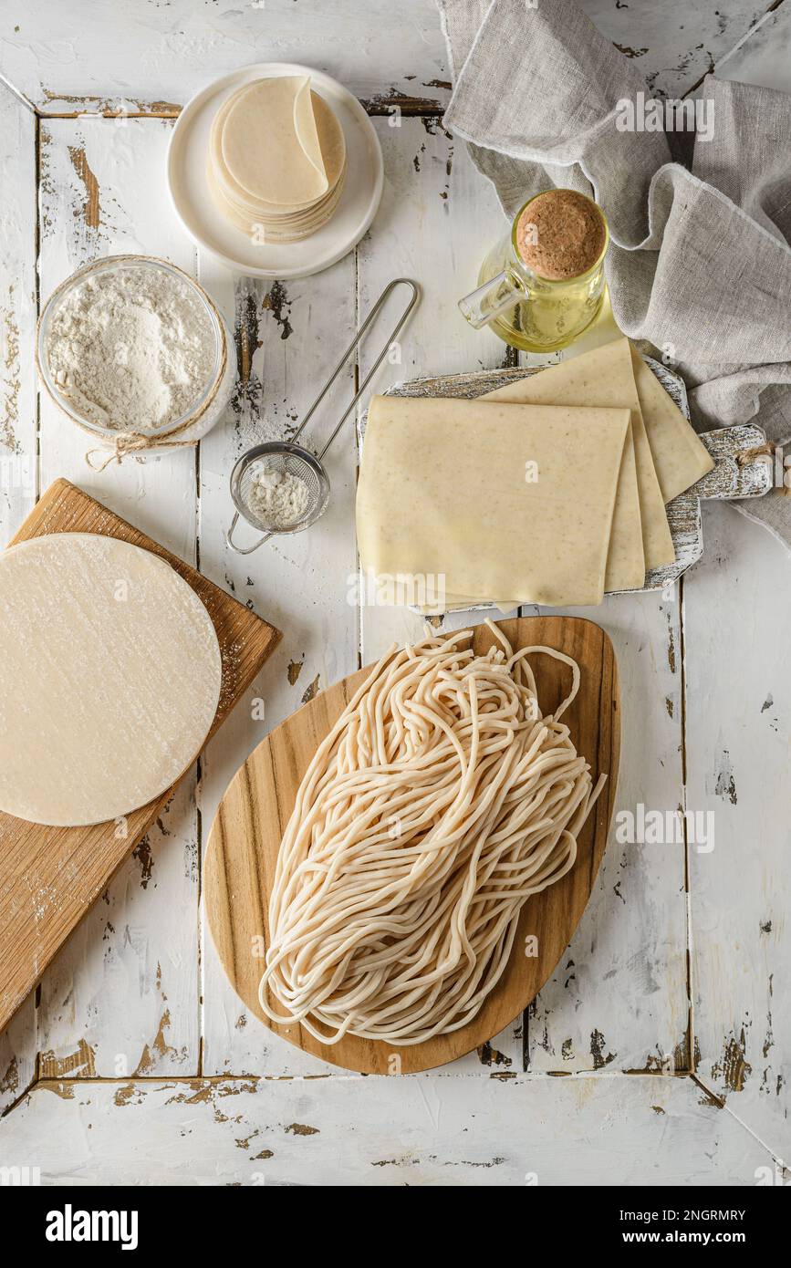 Verschiedene Arten von Teig. Teig für Teigtaschen, Teigtaschen, Pasties, Nudeln und Lasagne-Blätter auf weißem Holzhintergrund Stockfoto