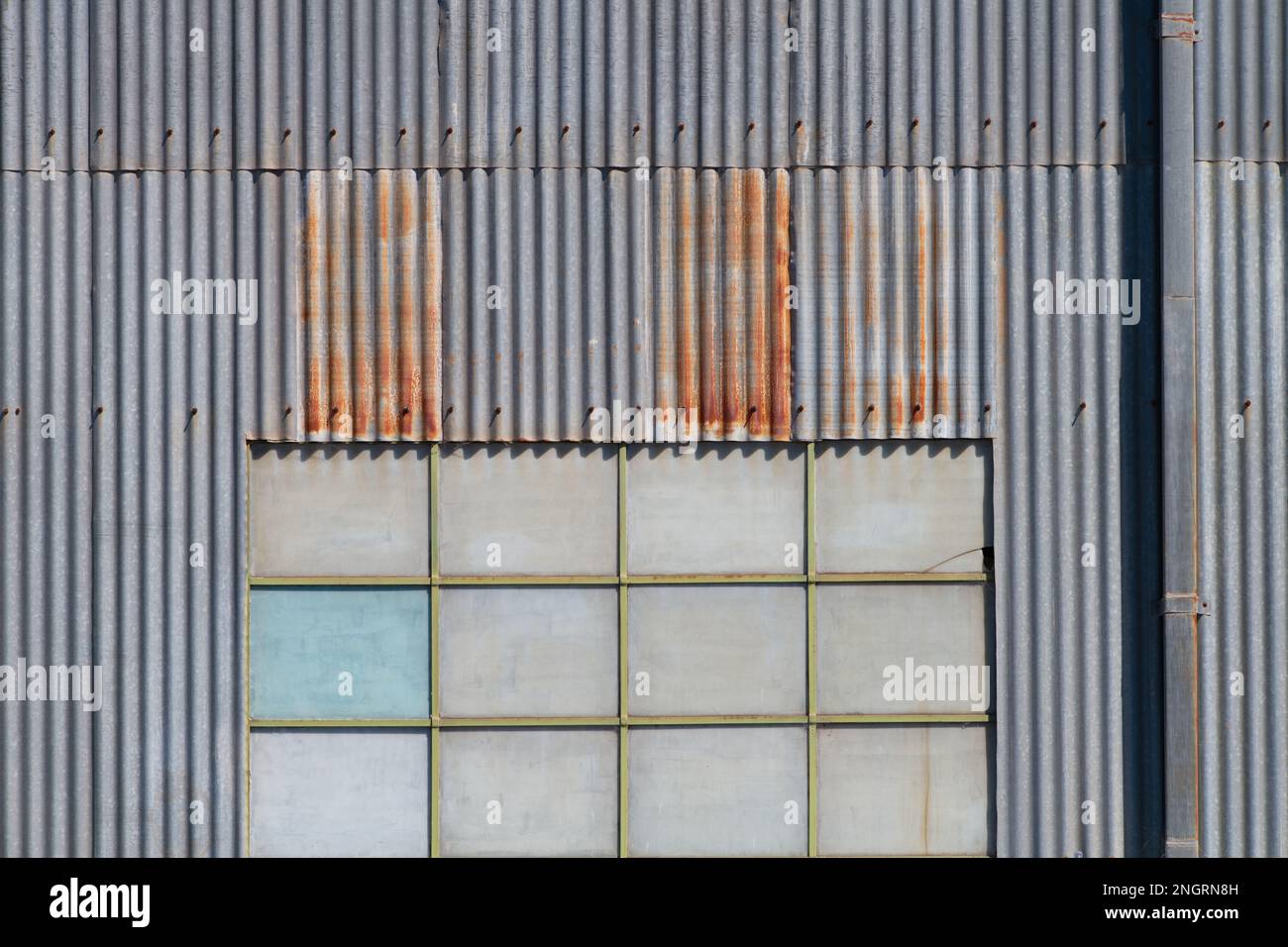 Metallhintergrundstruktur mit einer Wand und Fenstern einer Welleisenfabrik in Castlemaine, Australien. Stockfoto