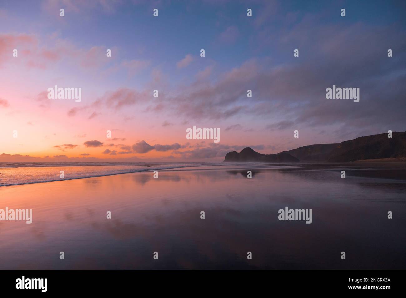 Ein atemberaubender Blick auf Bethells Beach, eingefangen bei Sonnenuntergang, mit lebhaften Pink-, Violett- und Orangentönen am Himmel. Stockfoto