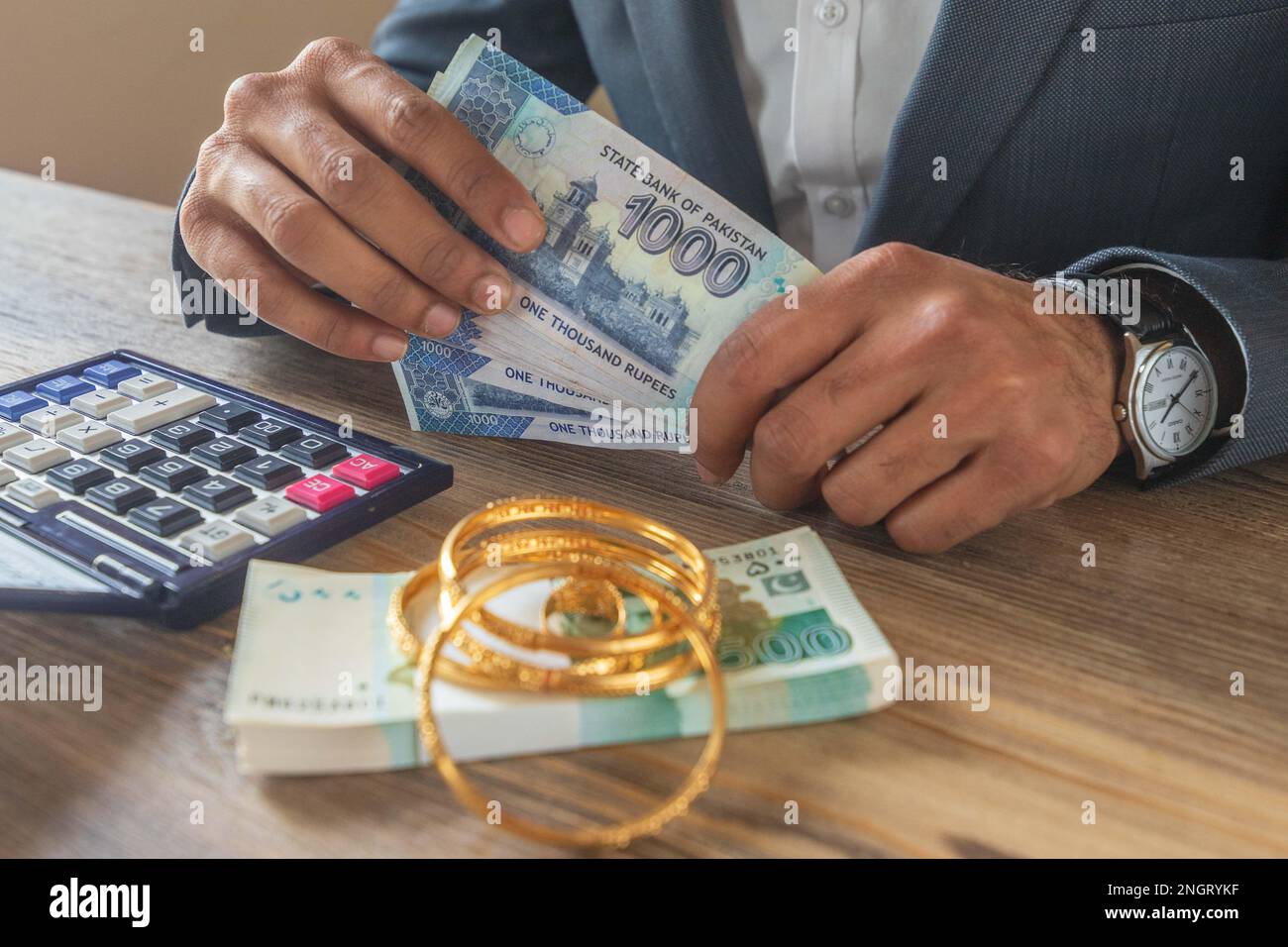 Ein Geschäftsmann, der mit pakistanischen Ehebrechern mit Währungsscheinen und Gold zu tun hat, um Geld zu sparen, Investitionen zu tätigen und die Finanzbuchhaltung zu verwalten oder zu wachsen Stockfoto