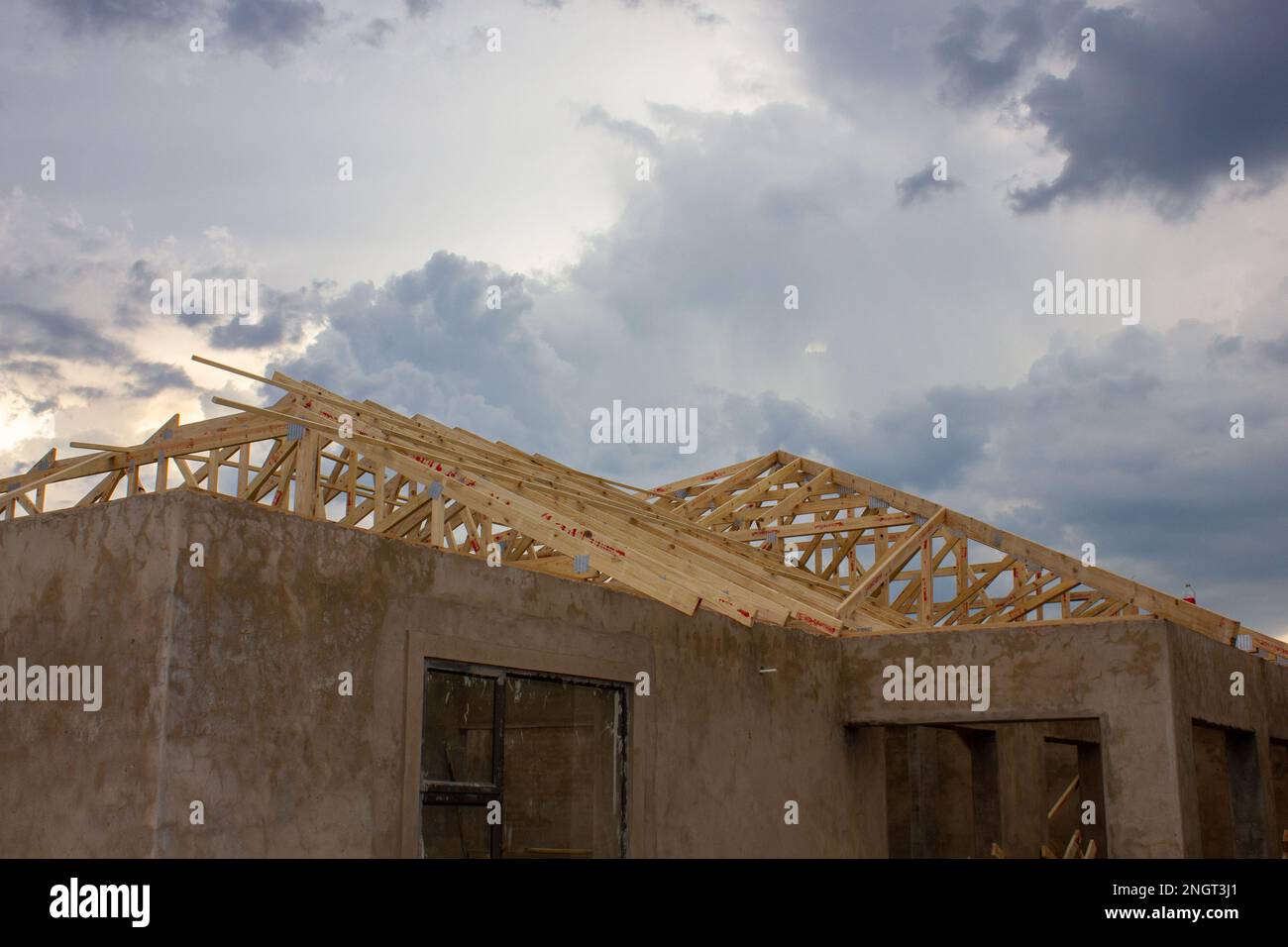 Unlackierte Putzwände und Holzdachbalken eines im Bau befindlichen Hauses. Stockfoto