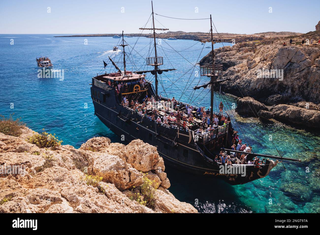 Touristenpiratenschiff neben dem Steinbogen Kamara tou Koraka im Cape Greco National Forest Park in Zypern Stockfoto