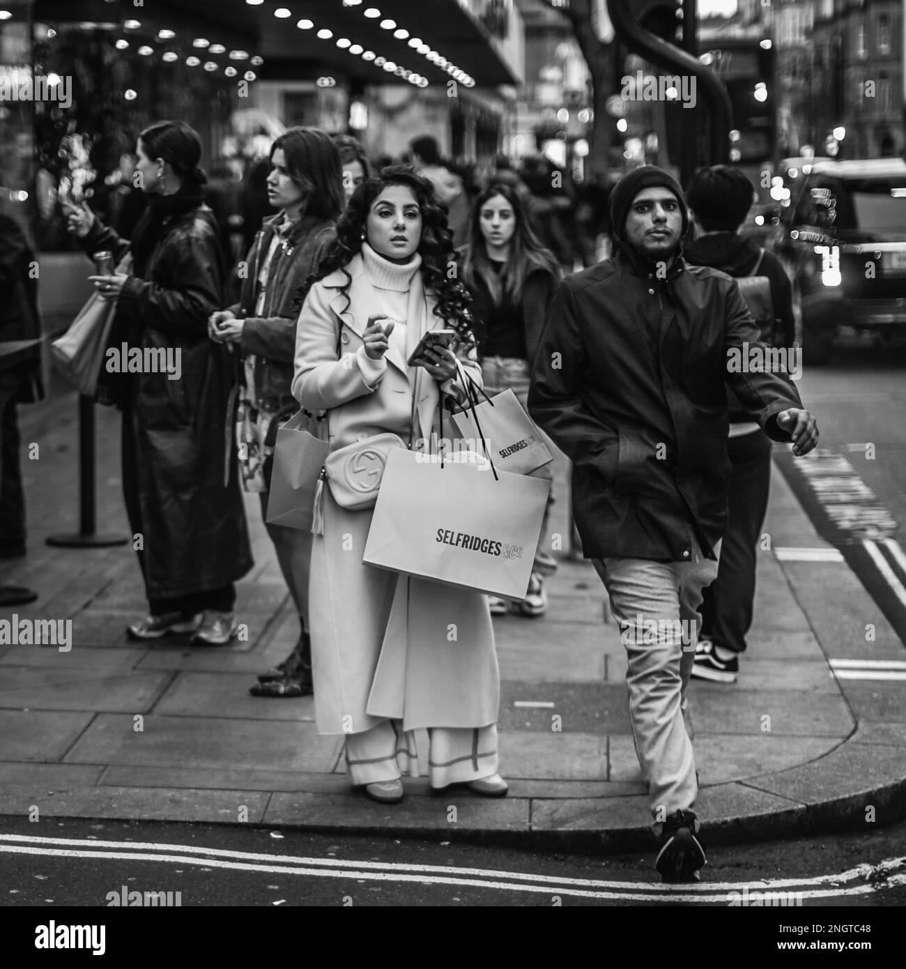 Ein Schwarzweißbild eines Käufers, der während der Londoner Fashionwoche in einer Menschenmenge in der Nähe von Londons Selfridge's steht. Stockfoto