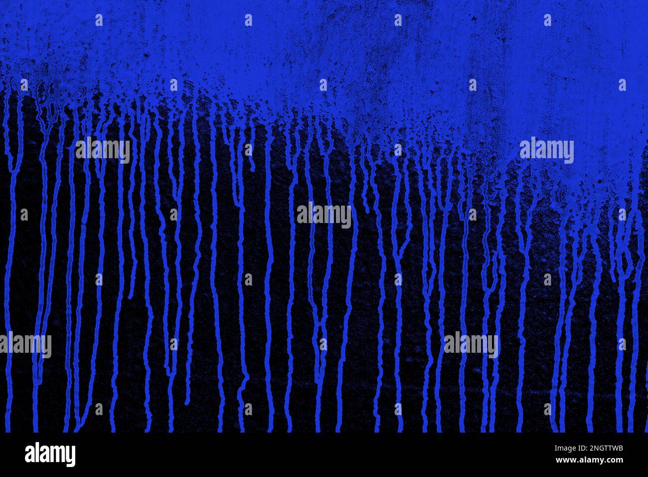 Blaue Farbe, die die dunkle Wand hinunterläuft, Farbspritzer Stockfoto