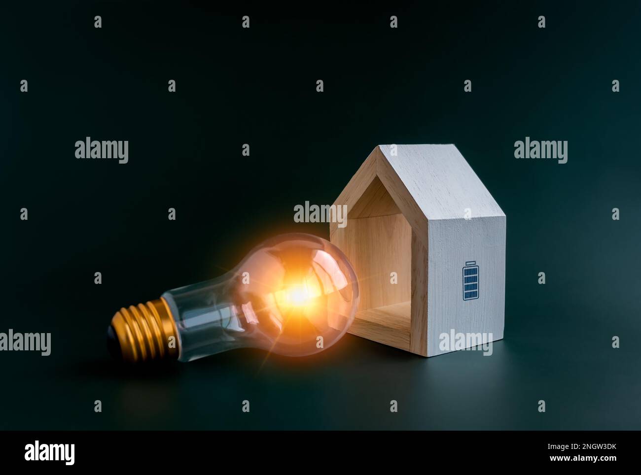 Energiesparend, Batteriesymbol auf weißem minimalistischem Holzhaus mit Glühbirne auf dunkelblauem Hintergrund. Intelligentes Zuhause mit Energiesparfunktion nachhaltig, Heim Stockfoto