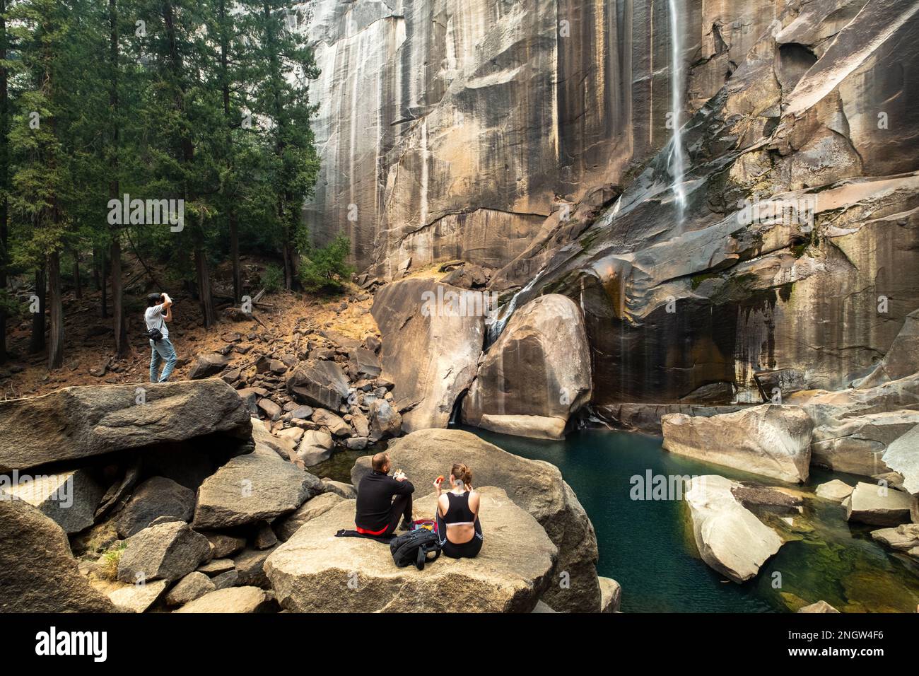 Ein Paar macht ein Picknick vor den Vernal Falls, während ein Mann ein Foto am Wasserfall Yosemite NP macht Stockfoto