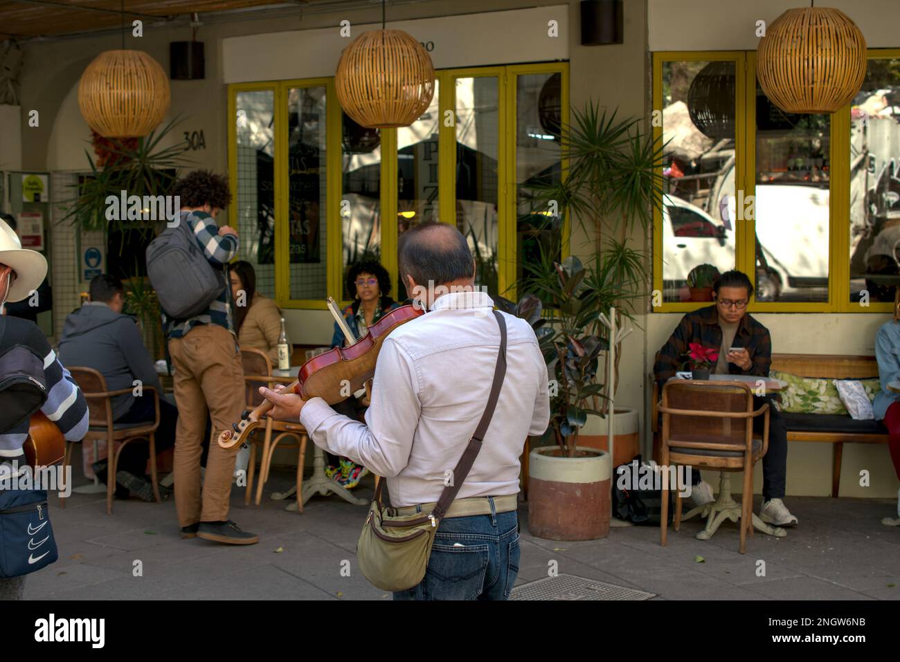 Straßengeiger spielt vor einem Café in Mexiko-Stadt Stockfoto