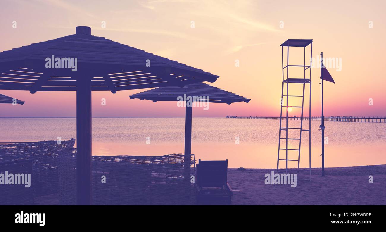 Die Silhouette des Rettungsschwimmturms am tropischen Strand bei Sonnenuntergang, Farbtönung, selektiver Fokus. Stockfoto