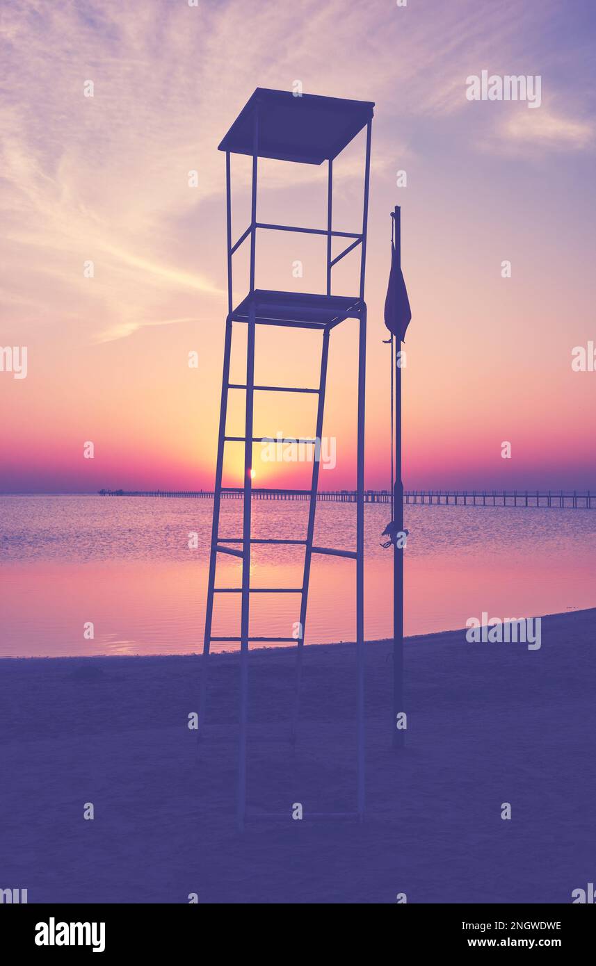 Die Silhouette des Rettungsschwimmturms am tropischen Strand bei Sonnenuntergang, Farbtönung, selektiver Fokus. Stockfoto