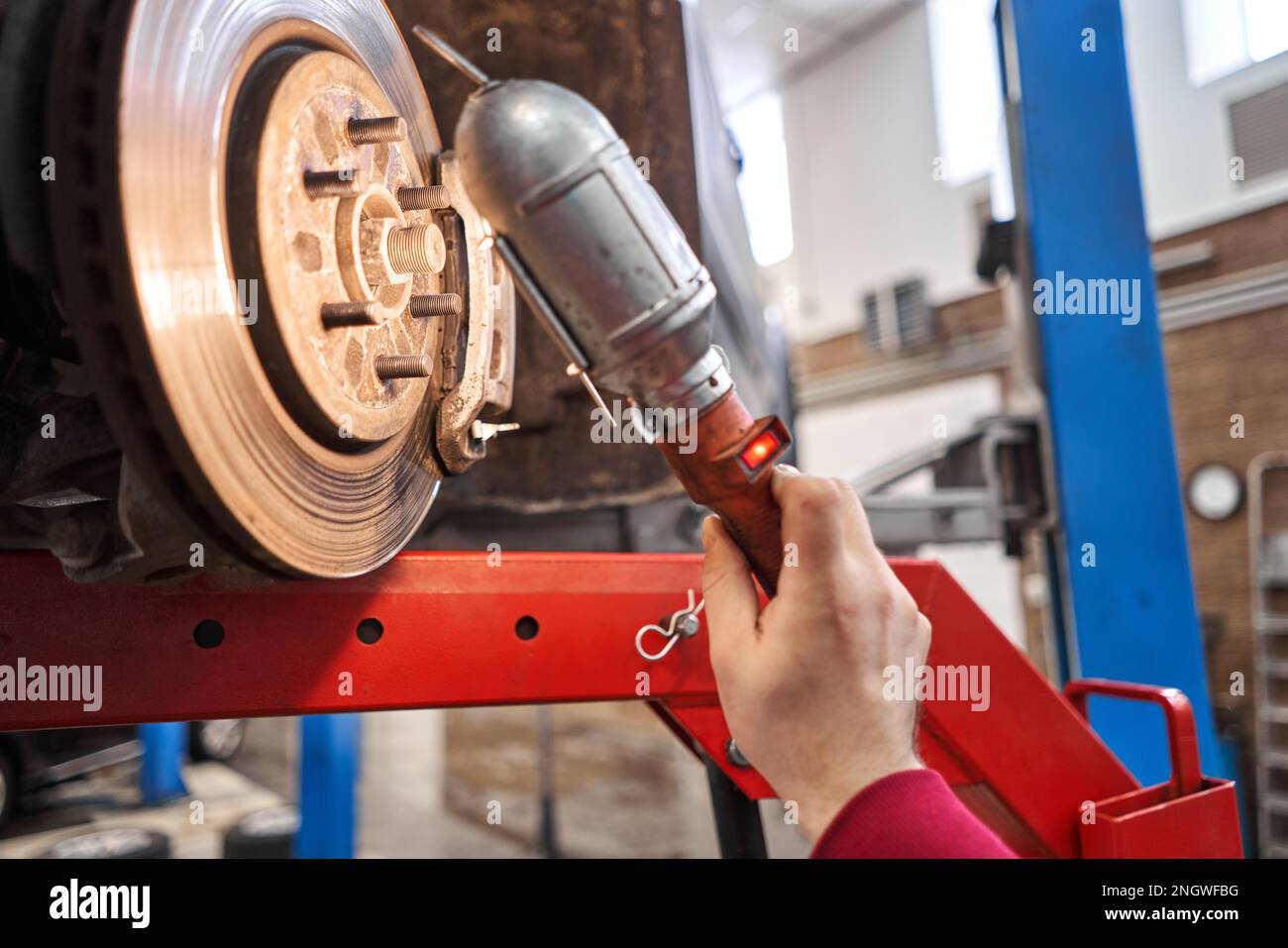 Ein Automechaniker inspiziert Bremsscheiben und Bremsbeläge mit einer Taschenlampe. Auto auf einem Reparaturständer. Technische Servicestation für Auto. Stockfoto