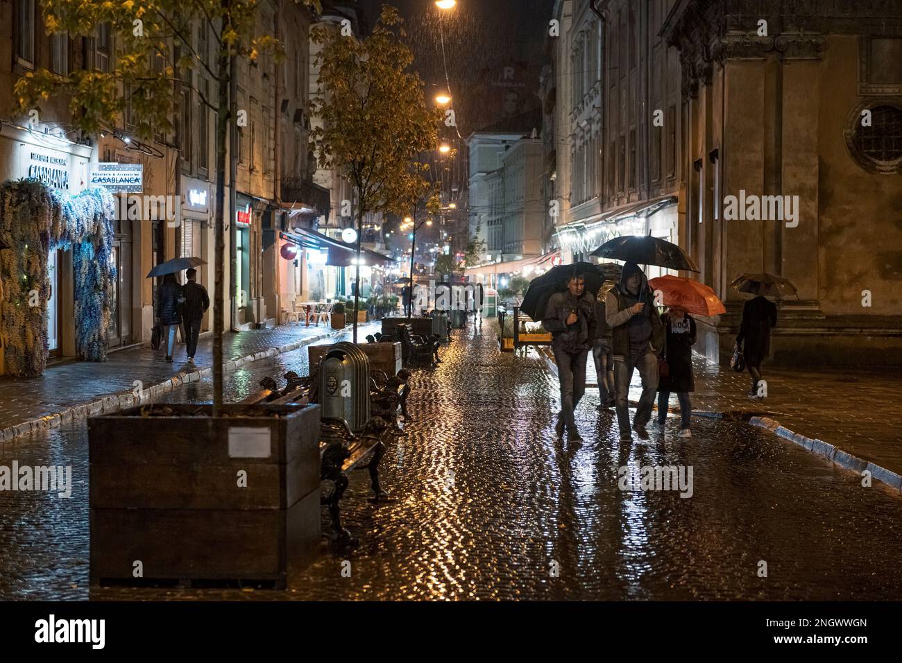 2020-09-29 Lemberg, Ukraine. Regnerische Nacht in der Altstadt. Fußgänger mit Sonnenschirmen auf nassen kopfsteingepflasterten Straßen Stockfoto