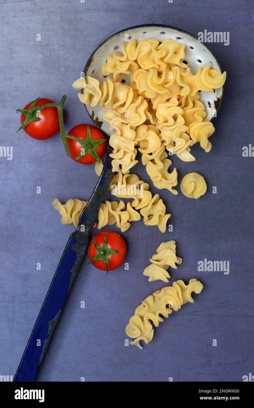 Pasta Capricci, Pasta aus Hartweizengrieß in einer Siebkelle und Tomaten Stockfoto