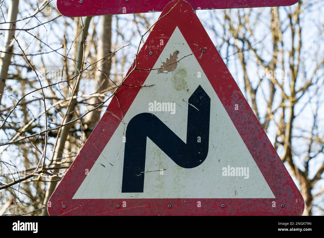Britisches Verkehrszeichen mit Hinweis auf kurvenreiche Straße mit einem gelesenen und weißen Warndreieck Stockfoto