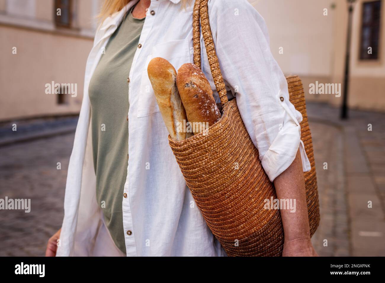 Frau mit Baguette-Brot im Strohsack. Nachhaltiger Lifestyle und wiederverwendbare Einkaufstasche Stockfoto