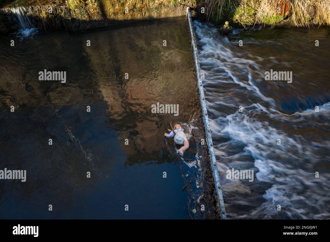Die Kinderpuppe hat sich in einem Metalleinzugsgebiet in einem schnell fließenden Fluss verfangen. Stockfoto