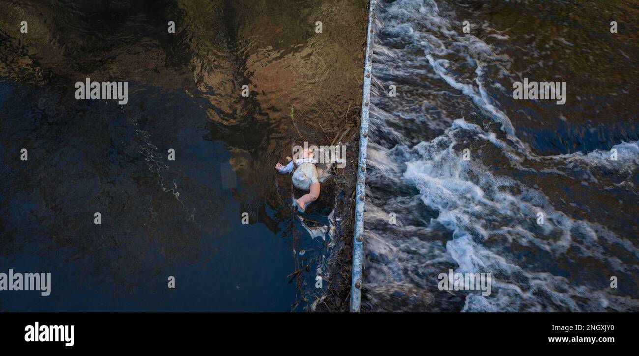 Die Kinderpuppe hat sich in einem Metalleinzugsgebiet in einem schnell fließenden Fluss verfangen. Stockfoto