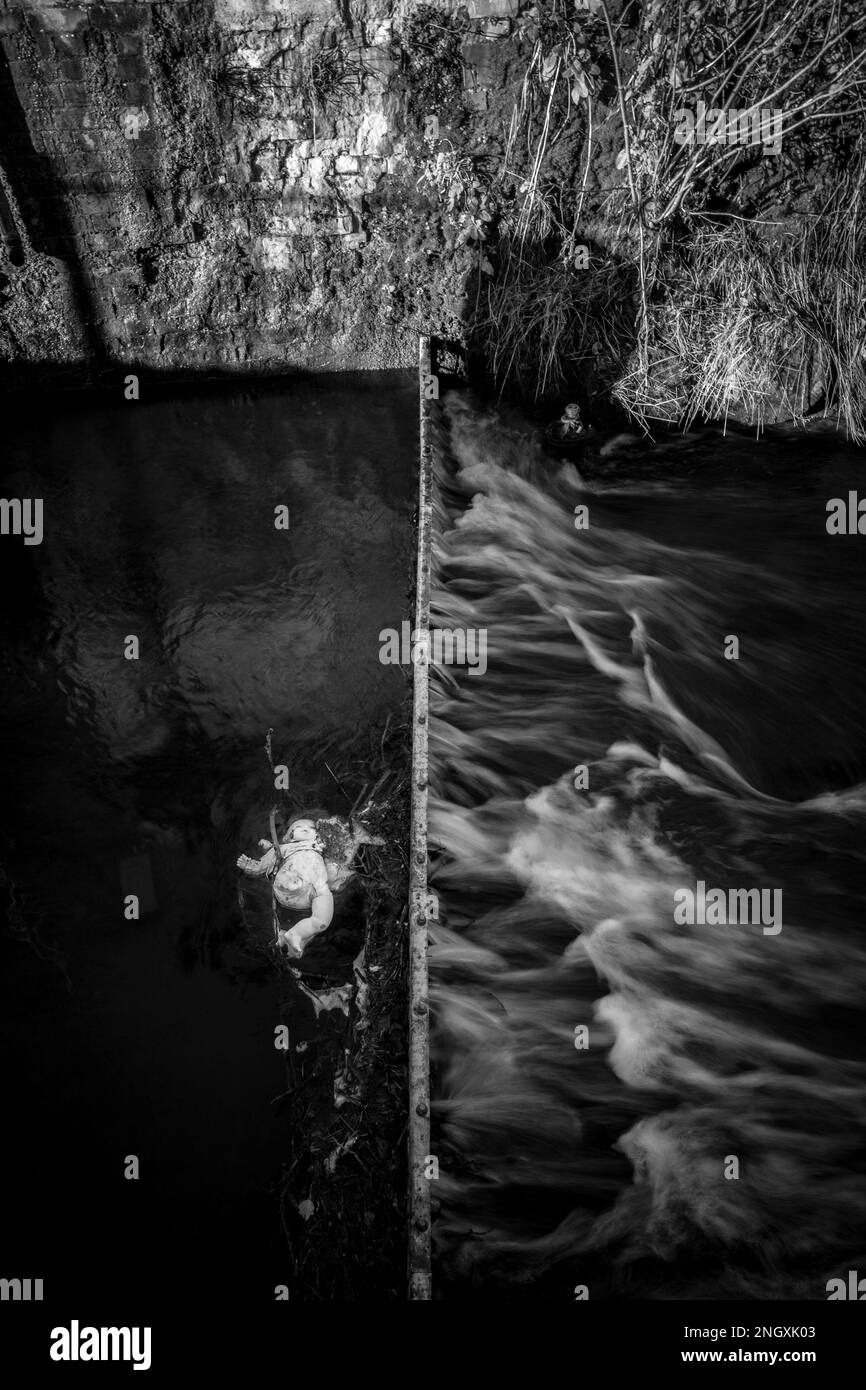 Die Kinderpuppe hat sich in einem Metalleinzugsgebiet in einem schnell fließenden Fluss verfangen. Stockfoto