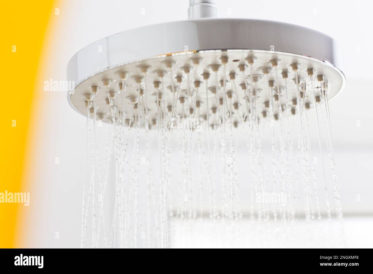 Fließendes Wasser aus einem Duschkopf in einem weißen, hellen Badezimmer - selektiver Fokus Stockfoto