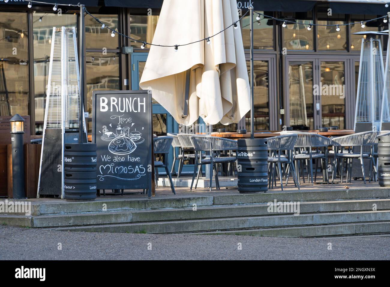 Der Speisesaal im Freien einer Bar, die an einem klaren, sonnigen Tag mit leeren Stühlen und Tischen für Brunch wirbt. Nach London Stockfoto
