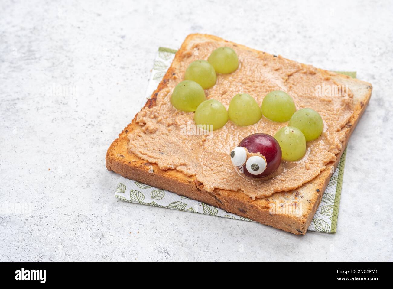 Lustiges Wurm-Sandwich mit Erdnussbutter und Trauben Stockfoto