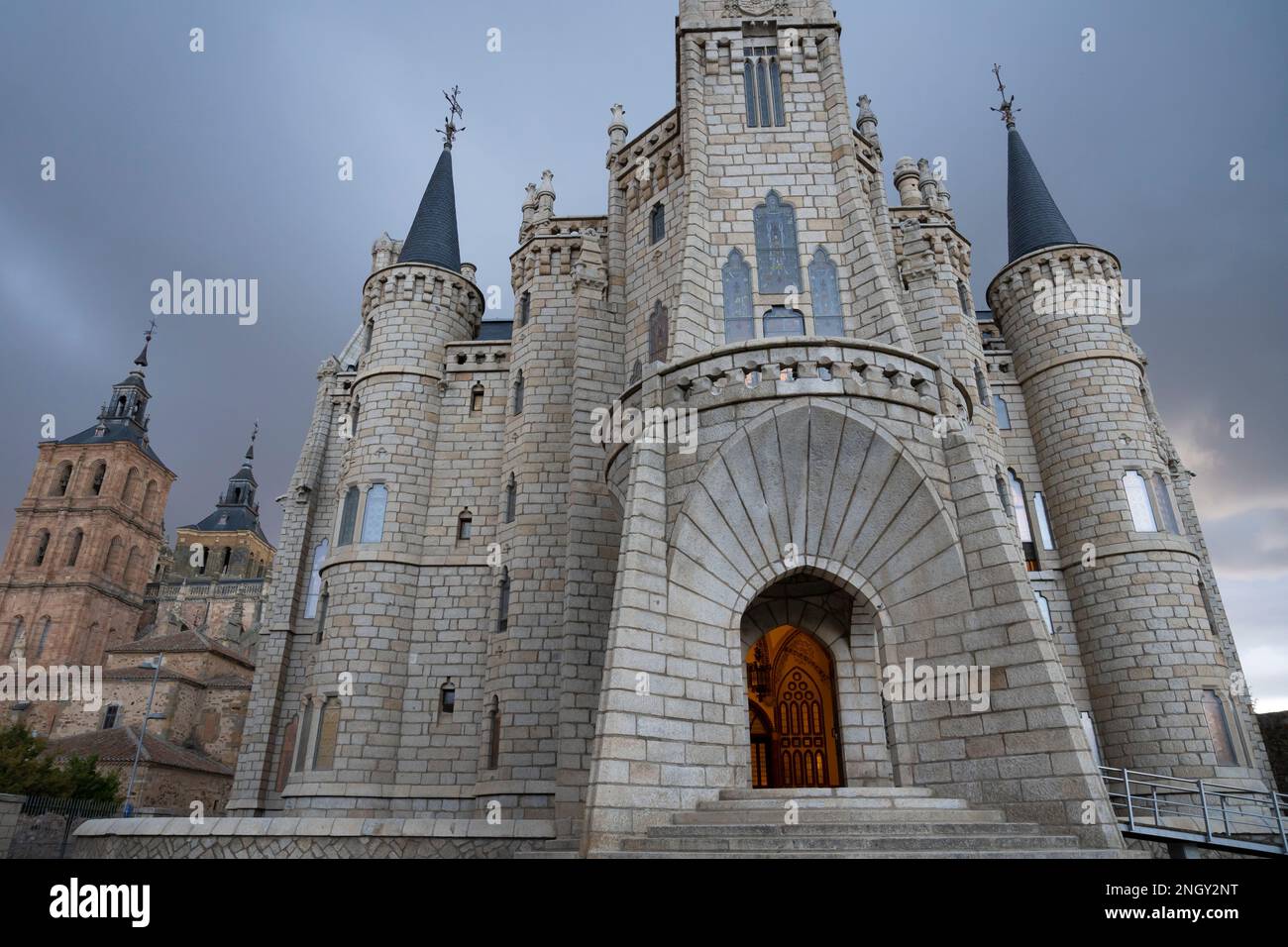 Der Eingang wird von einem warmen Licht erhellt, wenn sich im Episkopalpalast in Astorga, Leon, Spanien Sturmwolken sammeln. Das Wahrzeichen Gebäude von Katalanisch ar Stockfoto